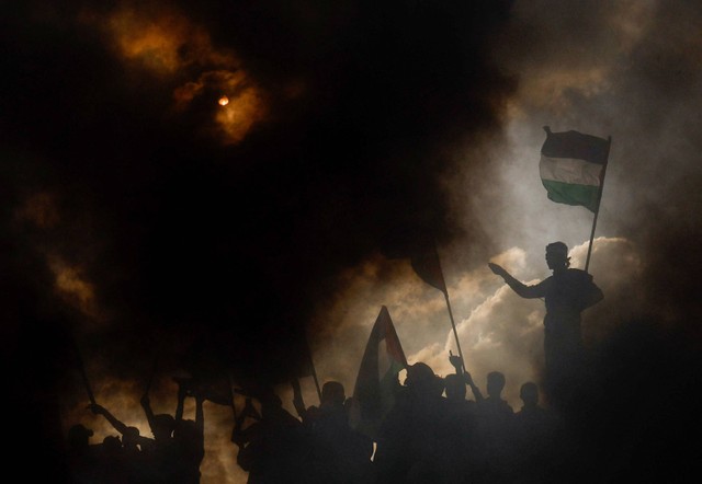 Warga Palestina mengambil bagian dalam protes menentang diadakannya pawai bendera tahunan di Yerusalem yang menandai Hari Yerusalem, di pagar perbatasan Israel-Gaza di timur Kota Gaza 18 Mei 2023. Foto: Mohammed Salem/Reuters