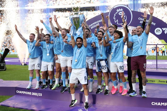 Pemain Manchester City Ilkay Gundogan mengangkat trofi saat selebrasi bersama rekan setim setelah memenangkan Liga Inggris, di Stadion Etihad, Manchester, Inggris, Minggu (21/5/2023). Foto: Carl Recine/REUTERS