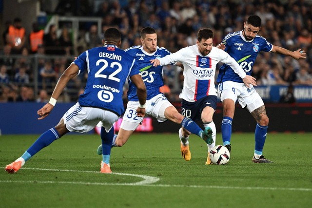 Lionel Messi (tengah) diadang saat laga PSG vs Strasbourg dalam pekan ke-37 Liga Prancis 2022/23 di Stade de la Meinau pada 28 Mei 2022. Foto: PATRICK HERTZOG / AFP