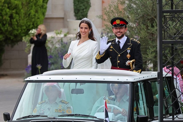 Putra Mahkota Yordania Hussein (kiri) dan istrinya Saudi Rajwa al-Seif pergi dalam konvoi setelah upacara pernikahan kerajaan mereka di Amman, Yordania, Kamis (1/6/2023). Foto: Khalil Mazraawi/AFP