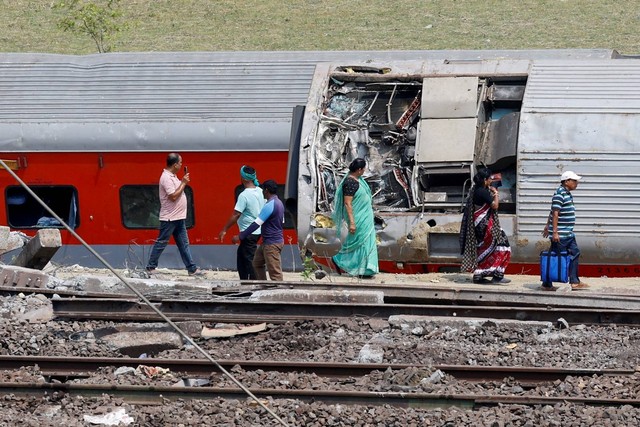 Orang-orang berjalan melewati gerbong yang rusak di lokasi tabrakan kereta setelah kecelakaan di distrik Balasore di negara bagian timur Odisha, India, Minggu (4/6/2023). Foto: Adnan Abidi/REUTERS