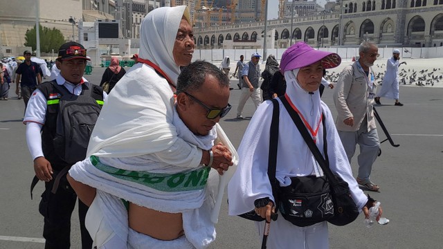 Seorang peserta ibadah haji menggendong jamaah lansia usai melakukan umrah di pelataran Masjidil Haram, Mekah, Arab Saudi, Selasa (6/6/2023). Foto: ANTARA FOTO/Wahyu Putro A