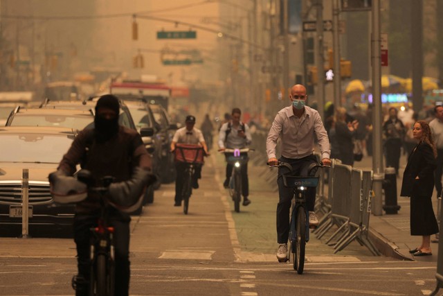 Orang-orang mengendarai sepeda di 6th Avenue saat kabut dan asap yang disebabkan oleh kebakaran hutan di Kanada menyelimuti Kota New York, New York, AS, Rabu (7/6/2023). Foto: Andrew Kelly/REUTERS