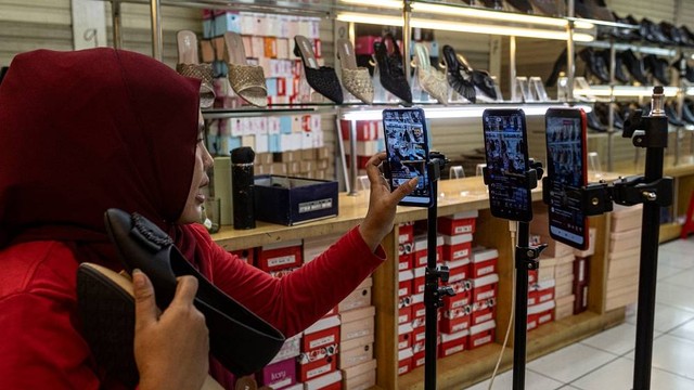 Pedagang menawarkan sepatu secara daring melalui siaran langsung di Pasar Tanah Abang, Jakarta, Selasa (13/6/2023). Foto: ANTARA FOTO/Aprillio Akbar