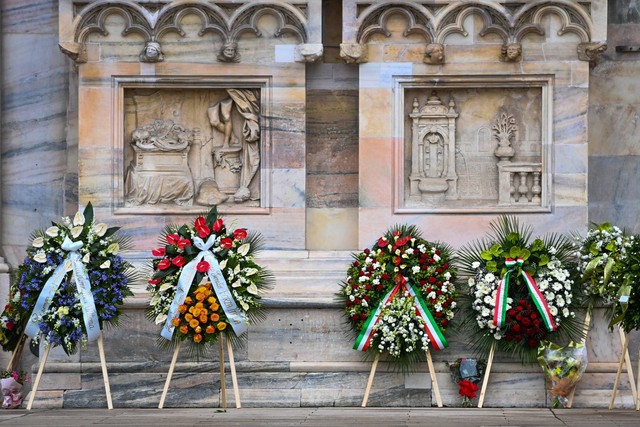 Karangan bunga diletakkan di depan katedral Duomo di Milan, menjelang pemakaman kenegaraan mantan perdana menteri Italia dan maestro media Silvio Berlusconi, Kamis (14/6/2023). Foto: Piero Cruciatti/AFP