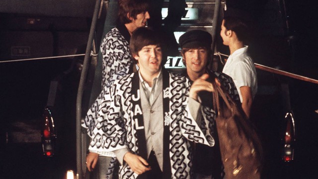 Anggota band Inggris The Beatles, Paul McCartney (kiri) dan John Lennon (kanan) serta George Harrison (belakang kiri) tiba di Bandara Internasional Tokyo di Haneda di Tokyo menjelang tur mereka pada tanggal 29 Juni 1966. Foto: Jiji Press / AFP