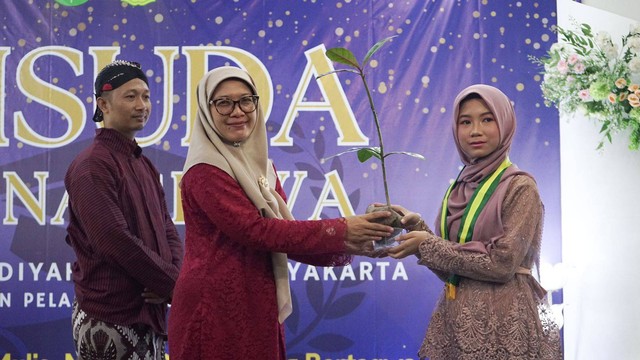 Kepala SD Muhammadiyah Kauman, Layin Fauziyah, menyerahkan bibit pohon keben kepada perwakilan siswa dalam acara wisuda pada Sabtu (17/6). Foto: Arif UT 