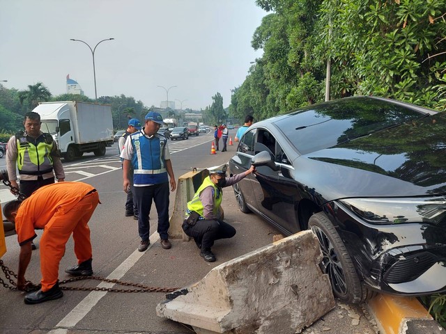 Petugas mengevakuasi mobil Mercy yang menabrak beton pembatas jalan di Tol JORR dekat gerbang Ciputat, Rabu (21/6). Foto: Dok. Istimewa