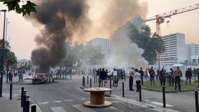 Asap mengepul dari kendaraan yang terbakar setelah bentrokan antara pengunjuk rasa dan polisi, di Toulouse, Prancis, Rabu (28/6/2023). Foto: Timothee Forget/via REUTERS