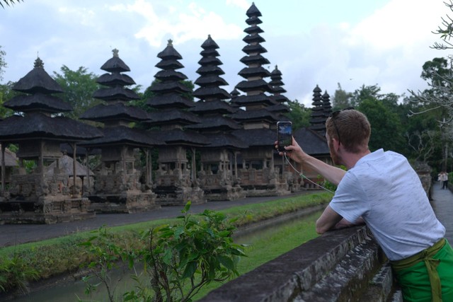 Wisatawan mancanegara memotret suasana saat mengunjungi Pura Taman Ayun di Desa Mengwi, Badung, Bali, Rabu (5/7/2023). Foto: Nyoman Hendra Wibowo/Antara Foto