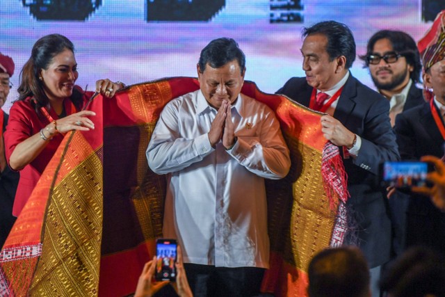 Menteri Pertahanan Prabowo Subianto (tengah) menerima pemakaian ulos oleh Ketua Umum PSBI Effendi MS Simbolon (kanan) dan istri Dessy Trinita br. Tobing (kiri) usai membuka kegiatan Rapat Kerja Nasional (Rakernas) PBSI 2023. Foto: Galih Pradipta/Antara Foto