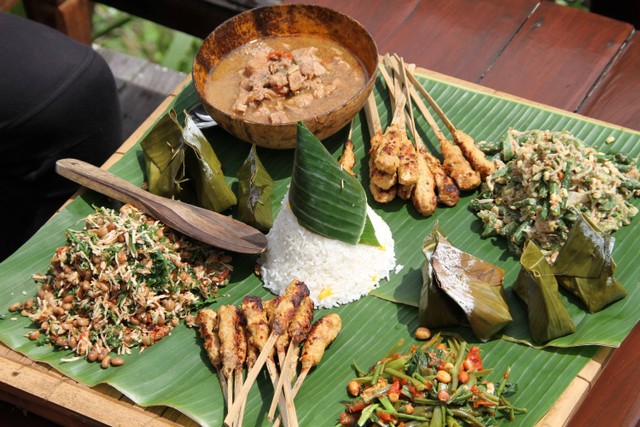 Ilustrasi megibung, tradisi kuliner makan bersama khas masyarakat Bali.  Foto: Shutterstock