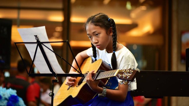 Seorang wanita bermain gitar. Foto: meesilpa sornsing/Shutterstock.