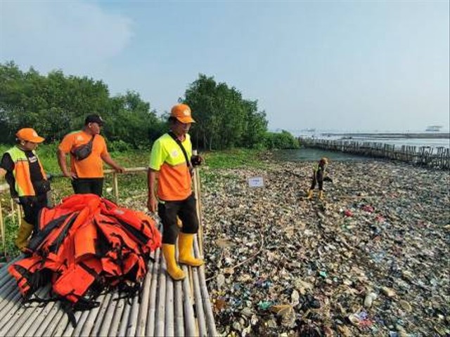 Personel bersihkan tumpukan sampah di pantai hutan mangrove Muara Angke. Foto: Pemprov DKI Jakarta