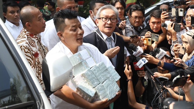 Tim kuasa hukum terdakwa korupsi BTS Kominfo, Irwan Hermawan membawa uang dalam bentuk dolar AS ke Kejagung, Jakarta, Kamis (13/7/2023). Foto: Dicky Adam Sidiq/kumparan