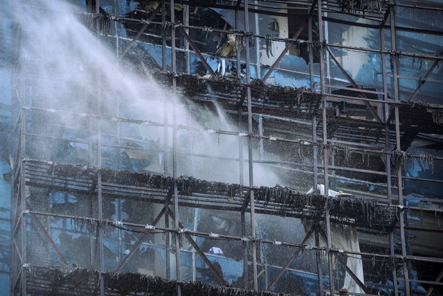 Petugas pemadam kebakaran dalam proses pendinginan di K-Link Tower, di Gatot Subroto, Jakarta, usai kebakaran, Sabtu (15/7/2023). Foto: Jamal Ramadhan/kumparan