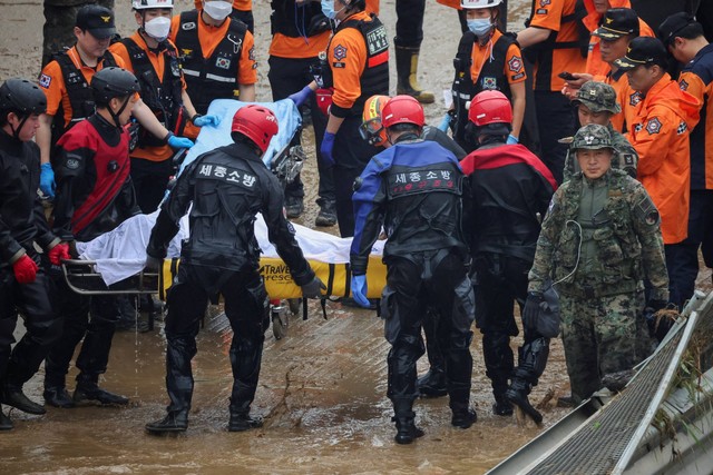 Petugas penyelamat membawa jenazah korban yang ditemukan selama operasi pencarian dan penyelamatan di dekat jalan bawah tanah yang terendam banjir akibat hujan deras di Cheongju, Korea Selatan, Minggu (16/7/2023). Foto: Kim Hong-Ji/REUTERS