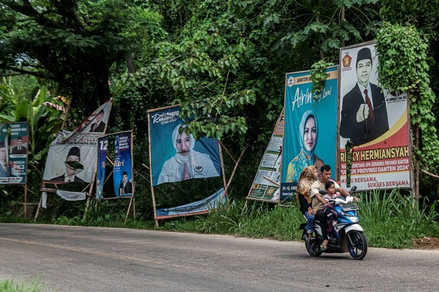 Pengendara roda dua melintas di samping baliho alat peraga kampanye (APK) di Pandeglang, Banten, Senin (17/7/2023). Foto: Muhammad Bagus Khoirunas/ANTARA FOTO