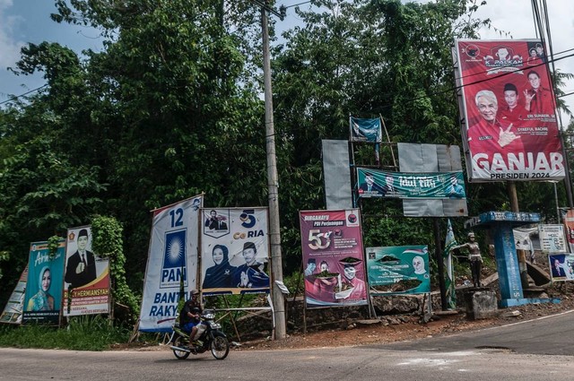 Pengendara roda dua melintas di samping baliho alat peraga kampanye (APK) di Pandeglang, Banten, Senin (17/7/2023). Foto: Muhammad Bagus Khoirunas/ANTARA FOTO