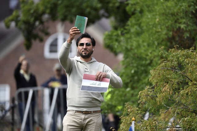 Pengunjuk rasa Salwan Momika berdiri di luar kedutaan Irak di Stockholm, Swedia, untuk membakar salinan Al-quran dan bendera Irak, Kamis (20/7/2023). Foto: Oscar Olsson/TT via AP