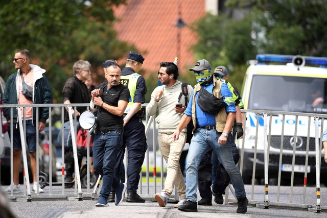 Pengunjuk rasa Salwan Momika, yang berencana membakar salinan Al-quran dan bendera Irak, dikawal polisi ke lokasi di luar kedutaan Irak, di Stockholm, Swedia, Kamis (20/7/2023). Foto: TT News Agency/Caisa Rasmussen via REUTERS