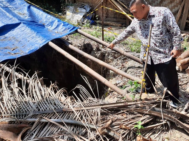 Kepala Perwakilan ORI DIY, Budhi Masthuri, menunjuk lubang hitam atau sinkhole misterius yang muncul di Dusun Klepu, Kalurahan Banjararum, Kalibawang, Kulon Progo. Foto: Dok. ORI DIY