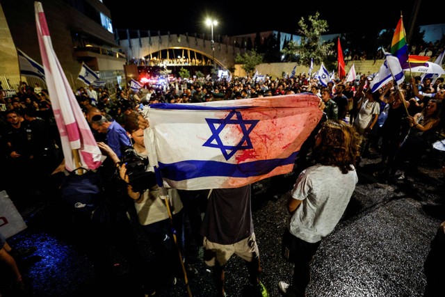 Seorang pengunjuk rasa memegang bendera bernoda merah di Yerusalem pada 24 Juli 2023.  Foto: Reuters/Amir Cohen