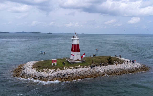 Foto udara sejumlah anggota TNI Polri bersama sejumlah instansi membersihkan kawasan menara mercusuar perbatasan laut Batam dan Singapura di Pulau Batu Berhenti, Belakang Padang, Batam, Kepulauan Riau, Senin (31/7/2023). Foto: Teguh Prihatna/Antara Foto