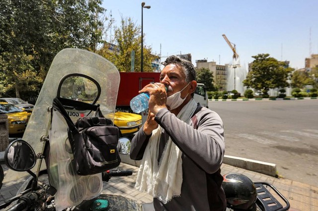 Seseorang membasuh wajah di tengah cuaca panas ekstrem di Iran. Foto: Asaad Niazi/AFP