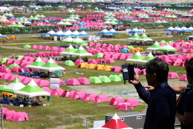 Seorang warga memfilmkan lokasi perkemahan Jambore Pramuka Dunia ke-25 di Buan, Korea Selatan, 4 Agustus 2023. Foto: Kim Hong-Ji/Reuters