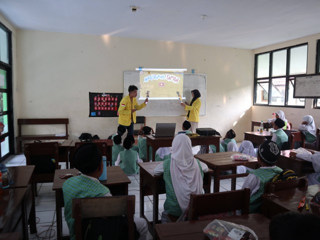 Youth (panitia UIYEA) memberikan presentasi edukasi lingkungan kepada siswa, menekankan pentingnya pelestarian lingkungan dalam program ini.