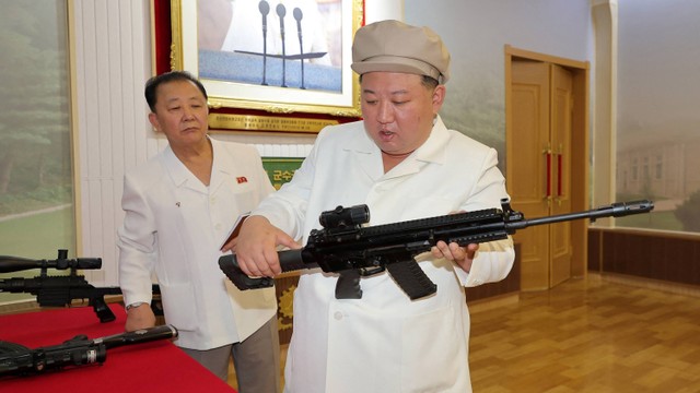 Pemimpin Korea Utara Kim Jong-un mencoba salah satu senjata saat meninjau pabrik senjata utama di Korea Utara. Foto: KCNA/via REUTERS