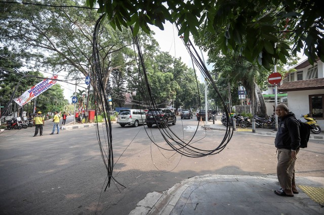 Petugas dari Dinas Bina Marga DKI Jakarta menata instalasi kabel yang semrawut di Jalan Yusuf Adiwinata, Menteng, Jakarta Pusat, Jumat (11/8/2023). Foto: Jamal Ramadhan/kumparan