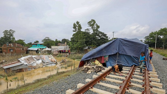 Orang-orang yang terkena dampak banjir berlindung di jalur kereta api setelah hujan lebat di Satkania, Bangladesh pada 13 Agustus 2023. Foto: AFP