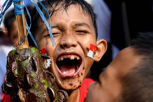 Peserta mengikuti lomba mengambil koin dari pepaya yang dilumuri cokelat di kawasan Petamburan, Jakarta, Kamis (17/8/2023). Foto: M Risyal Hidayat/ANTARA FOTO