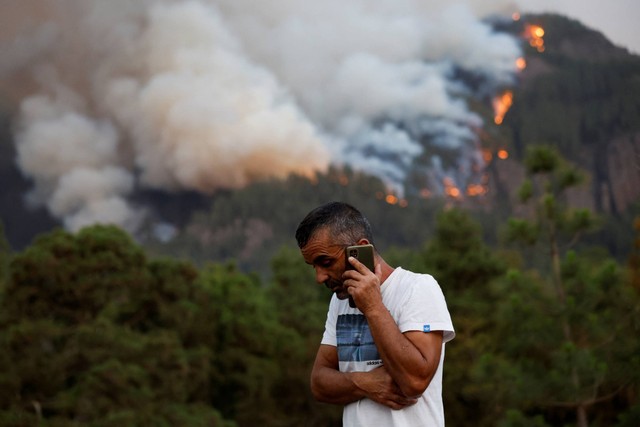 Penduduk kota Aguamansa menggunakan telepon seluler, saat kebakaran hutan mengamuk di luar kendali di pulau Tenerife, Kepulauan Canary, Spanyol, Kamis (17/8/2023). Foto: Borja Suarez/REUTERS