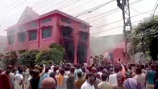 Orang-orang menyaksikan asap mengepul dari gedung gereja di Jaranwala, Pakistan, Rabu (16/8/2023). Foto: REUTERS TV via REUTERS