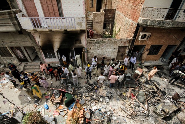 Orang-orang dan anggota media berkumpul di sepanjang jalan di lingkungan Kristen, sehari setelah gedung gereja dan rumah dirusak oleh pengunjuk rasa di Jaranwala, Pakistan, Kamis (17/8/2023). Foto: Muhammad Tahir/REUTERS