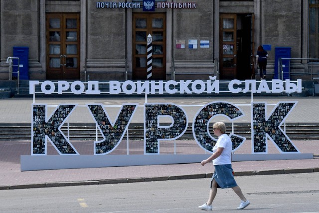 Seorang wanita berjalan melewati tanda bertuliskan "Kursk, kota kejayaan militer" di kota Kursk, Rusia. Foto: Olga MALTSEVA / AFP