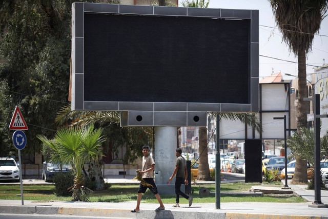 Kendaraan melewati layar iklan tertutup di alun-alun Uqba Bin Nafia di Baghdad pada Minggu (20/8/2023). Foto: Ahmad Al-Rubaye/AFP