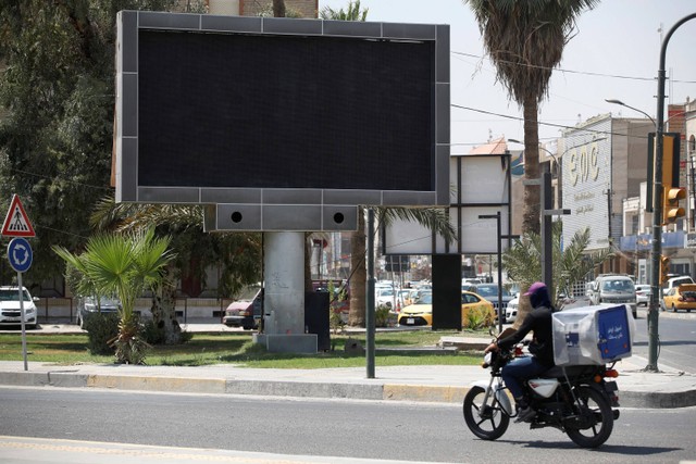 Kendaraan melewati layar iklan tertutup di alun-alun Uqba Bin Nafia di Baghdad pada Minggu (20/8/2023). Foto: Ahmad Al-Rubaye/AFP