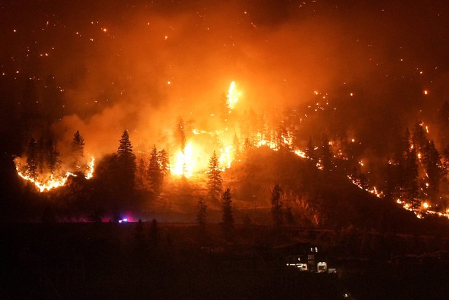 Kebakaran McDougall Creek membakar lereng gunung di atas rumah tepi danau di West Kelowna, Kanada, Jumat (18/8/2023).  Foto: Darryl Dyck/The Canadian Press via AP