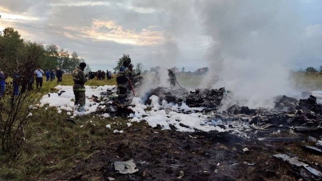 Petugas pemadam kebakaran bekerja di tengah puing-puing pesawat di lokasi kecelakaan menyusul jatuhnya jet pribadi di wilayah Tver, Rusia, Rabu (23/8/2023). Foto: Komite Investigasi Rusia/Handout via REUTERS