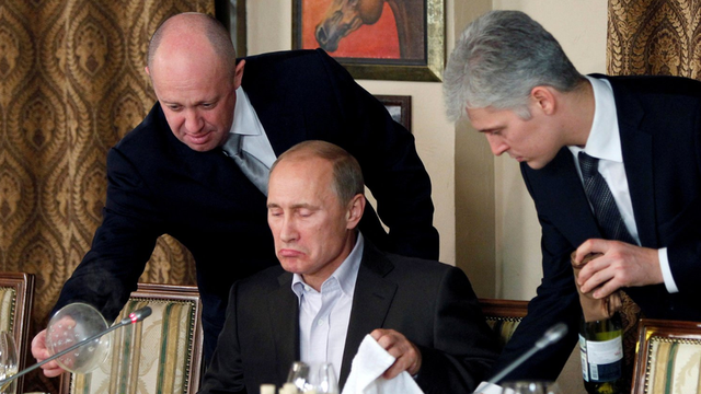 Yevgeny Prigozhin (kiri) melayani Vladimir Putin (tengah) pada suatu acara makan malam pada 2011.