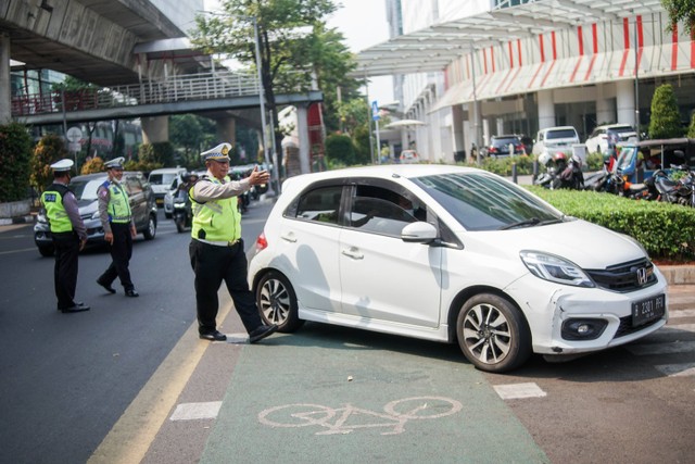 Polisi lalu lintas menghentikan kendaraan saat uji coba razia tilang uji emisi di Terminal Blok M, Jakarta Selatan, Jumat (25/8/2023). Foto: Jamal Ramadhan/kumparan