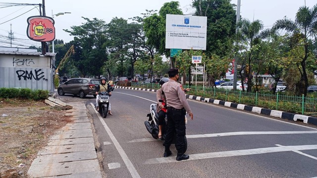 Polisi dari Polsek Jagakarsa mengadang pemotor yang lawan arah di Jalan Raya Lenteng Agung arah Depok di titik pintu kereta Gardu Srengseng Sawah, Senin (28/8/2023). Foto: Thomas Bosco/kumparan