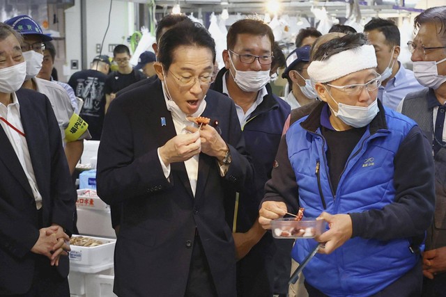 Perdana Menteri Jepang Fumio Kishida mencicipi makanan laut dari wilayah Fukushima saat berkunjung ke pasar ikan Toyosu di Tokyo, Jepang. Foto: Kyodo/via REUTERS