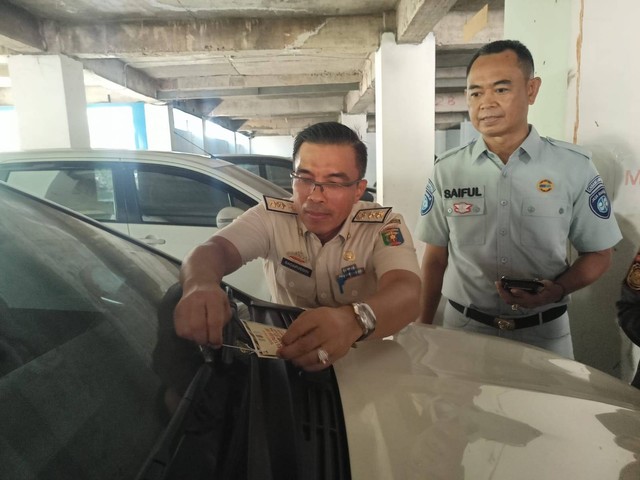 Petugas saat memasang stiker pemberitahuan terhadap kendaraan yang menunggak pajak. | Foto : Galih Prihantoro/ Lampung Geh
