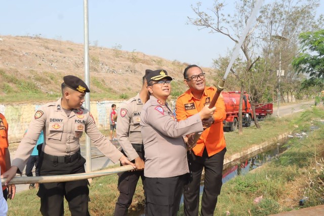 Kapolres Indramayu, AKBP M. Fahri Siregar menyemprotkan air ke tumpukan sampah di TPA Pecuk. Foto : Istimewa