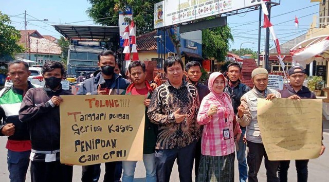 Para calon pekerja migran yang gagal berangkat kerja ke Polandia foto bersama kuasa hukumnya sambil menunjukkan kertas permintaan tolong ke Polisi di depan Mapolres Cirebon Kota. Foto : Istimewa